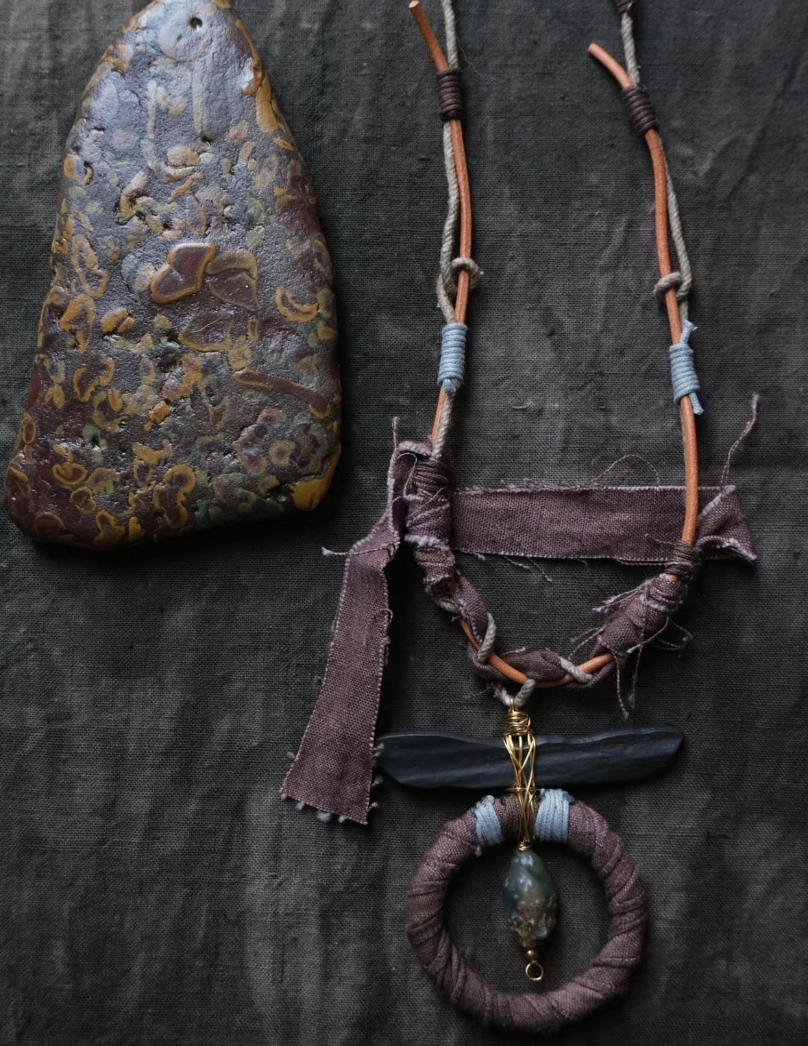 Artisan textile necklace in earthy tones with wrapped pendant detail and handcrafted boho texture