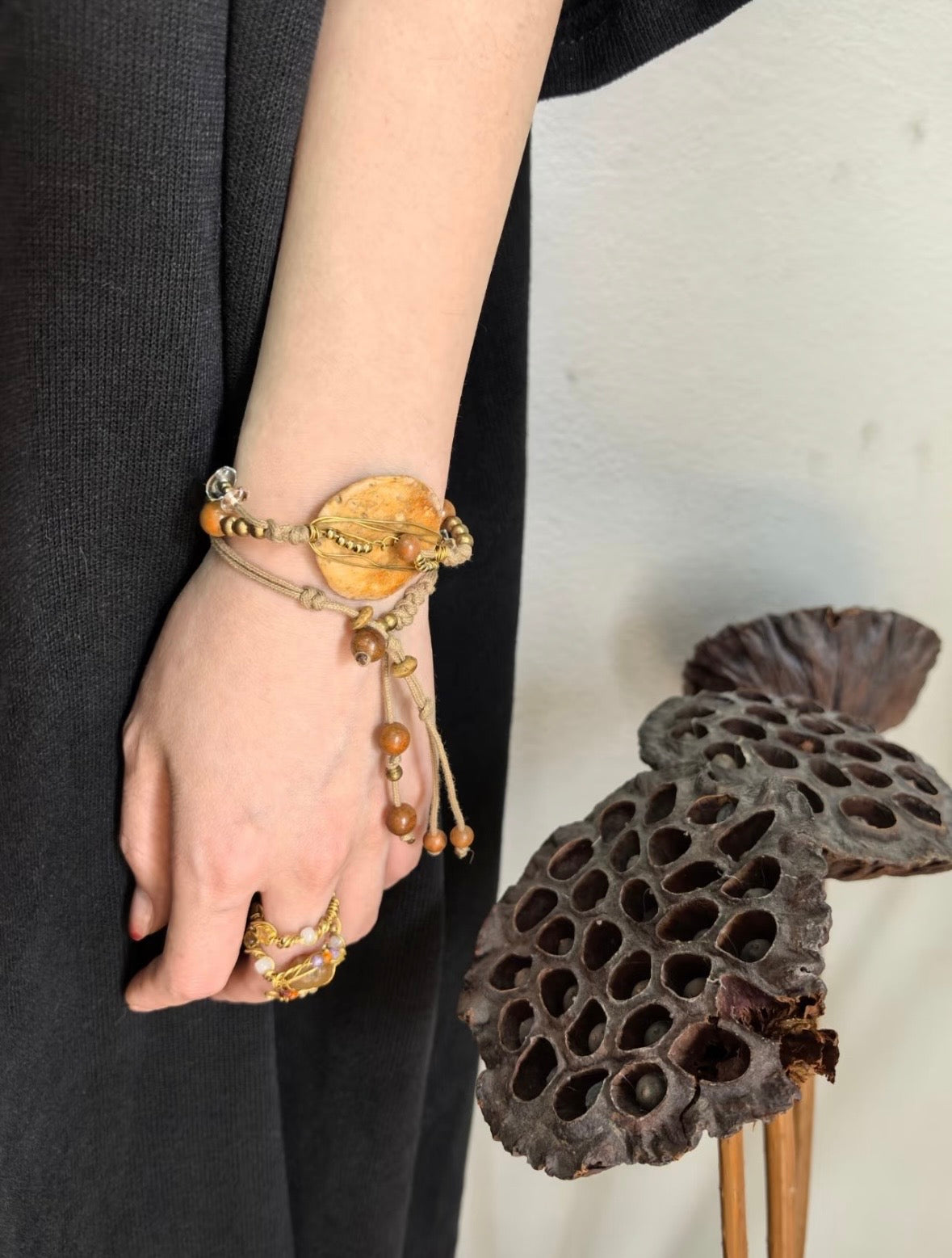 Handmade nummulite fossil bracelet worn on the wrist with brass wire, wood beads, and adjustable cord