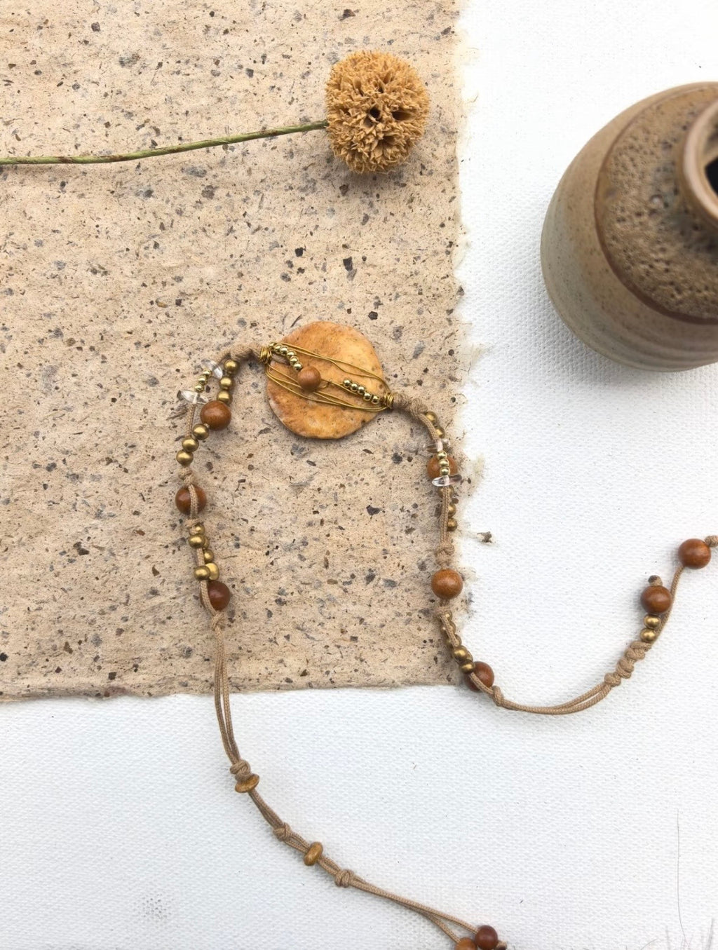 Flat lay of a handmade nummulite fossil necklace bracelet with brass wire and wood bead accents