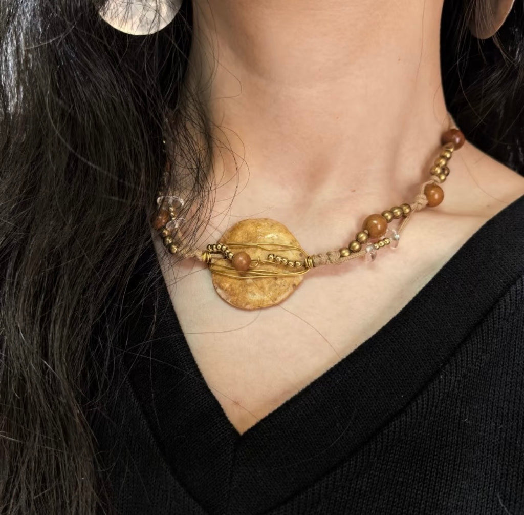 Handmade nummulite fossil necklace worn on the neck with brass wire and wood bead details